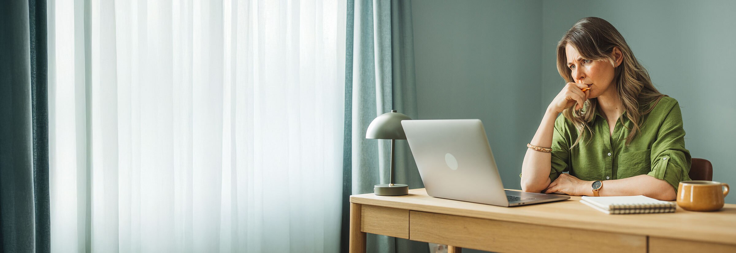 A woman looking at her laptop with a worried expression, potentially because confidential information was sent to wrong email.