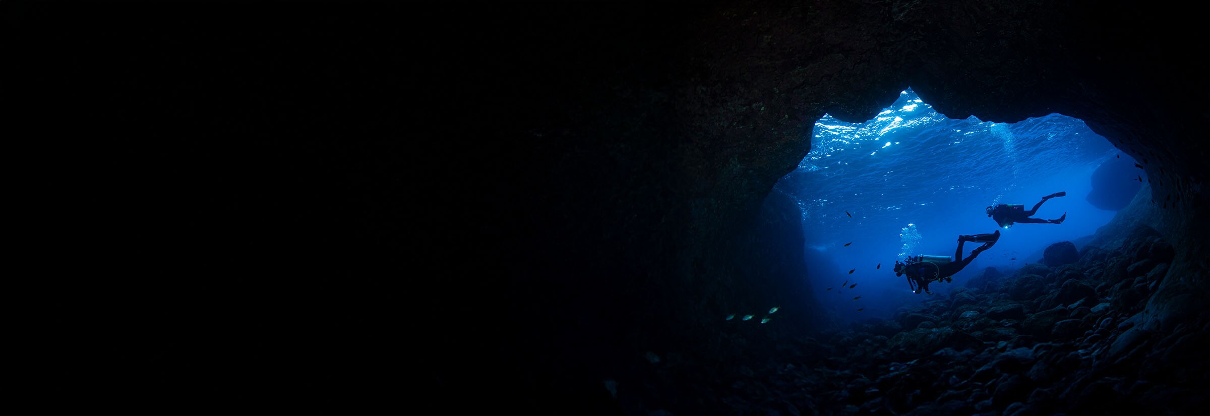 Divers exploring a deep, undersea cave, representing scanning the dark web.