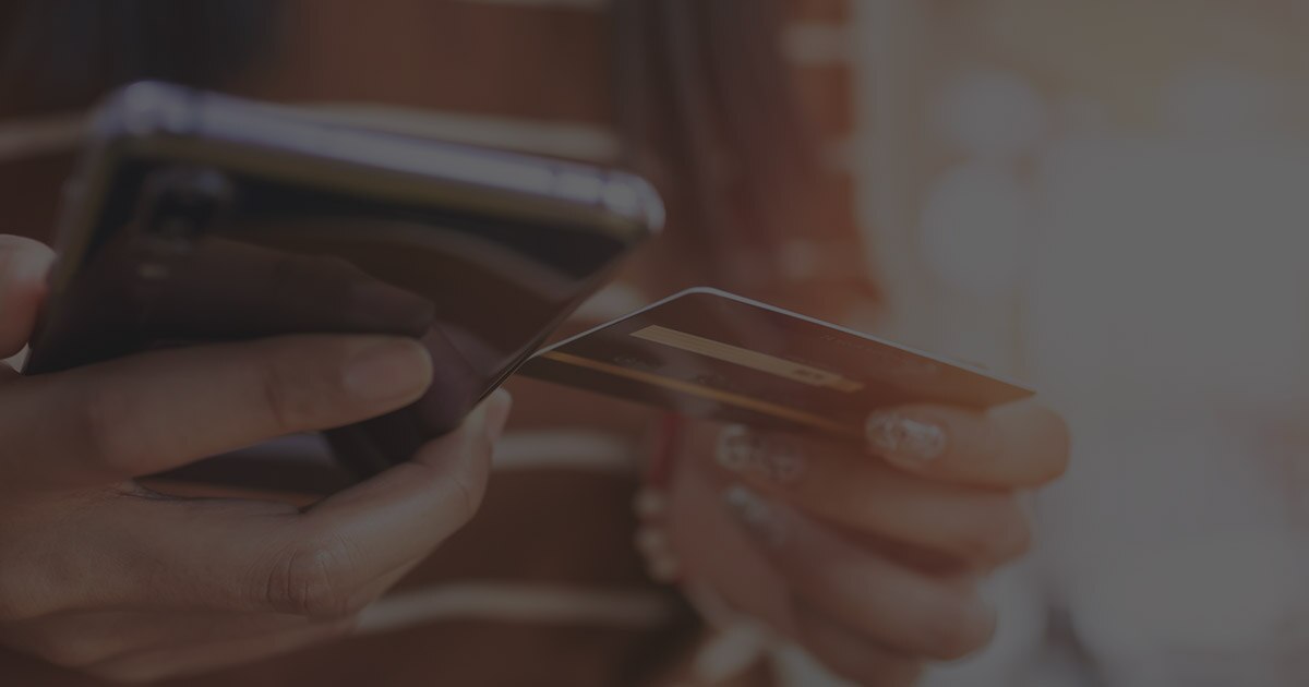 A person holding their phone and credit card trying to recover from a scam.