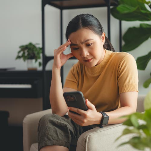 A person looks worried while staring at their phone because they accidentally opened a spam email.