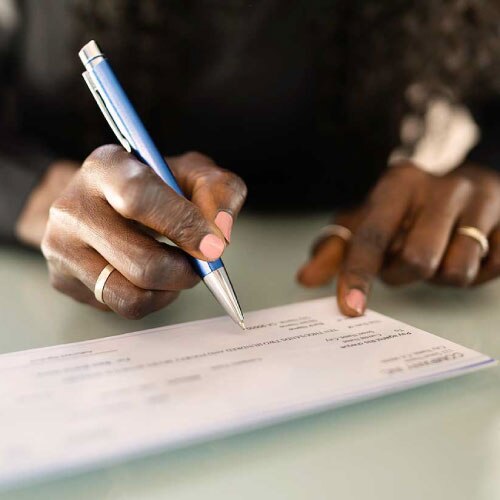 Someone writing a new check to be sent in the mail, hoping they don’t become a victim of check washing.