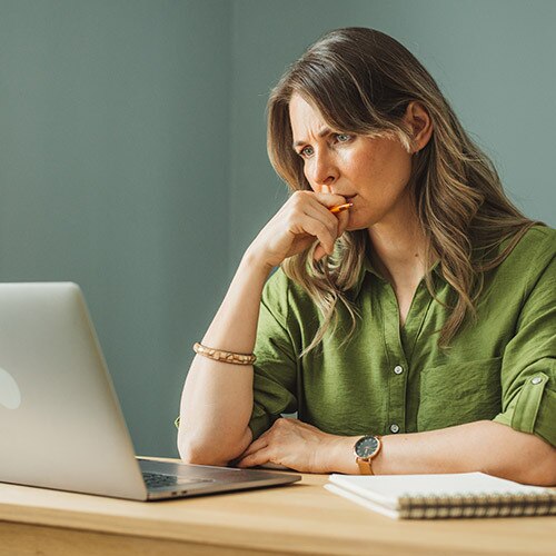 A woman looking at her laptop with a worried expression, potentially because confidential information was sent to wrong email.