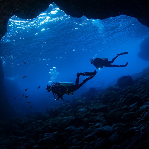 Divers exploring a deep, undersea cave, representing scanning the dark web.