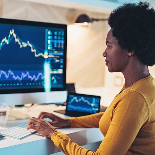 A woman looking at a screen displaying data trends.